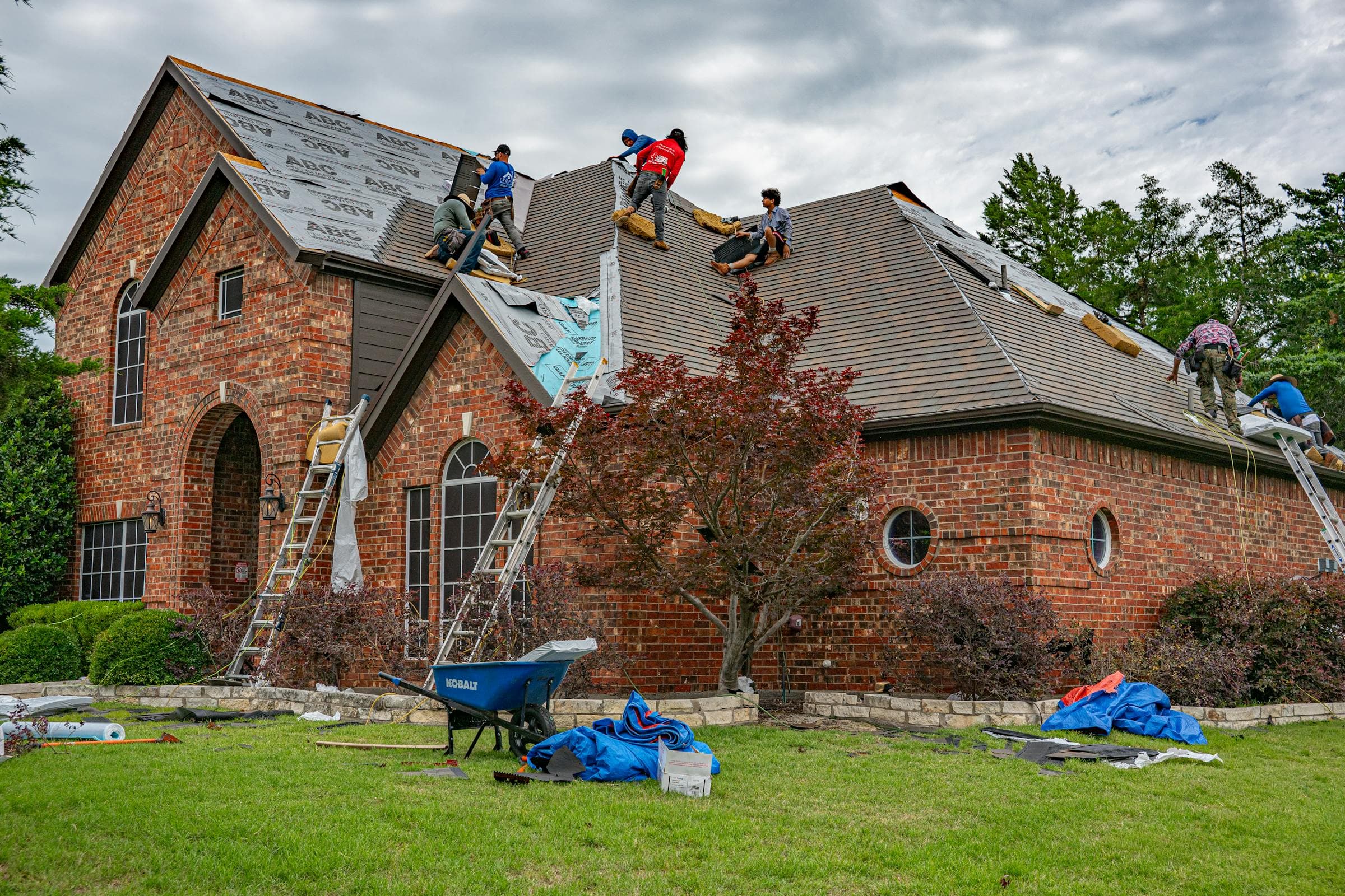 Roofing crew installing a new roof on a brick residential home