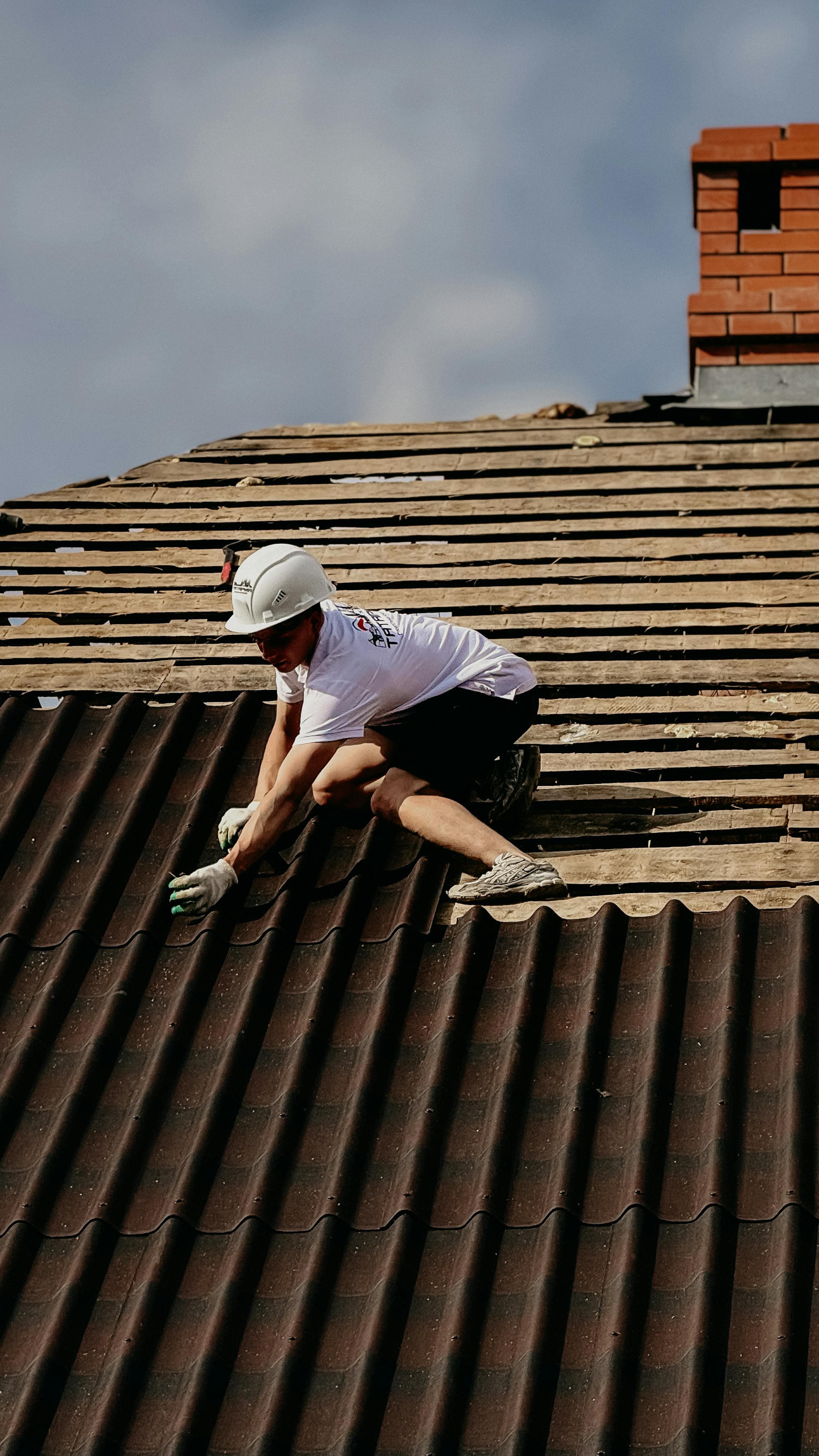 Roofer in safety gear repairing tile on a residential roof