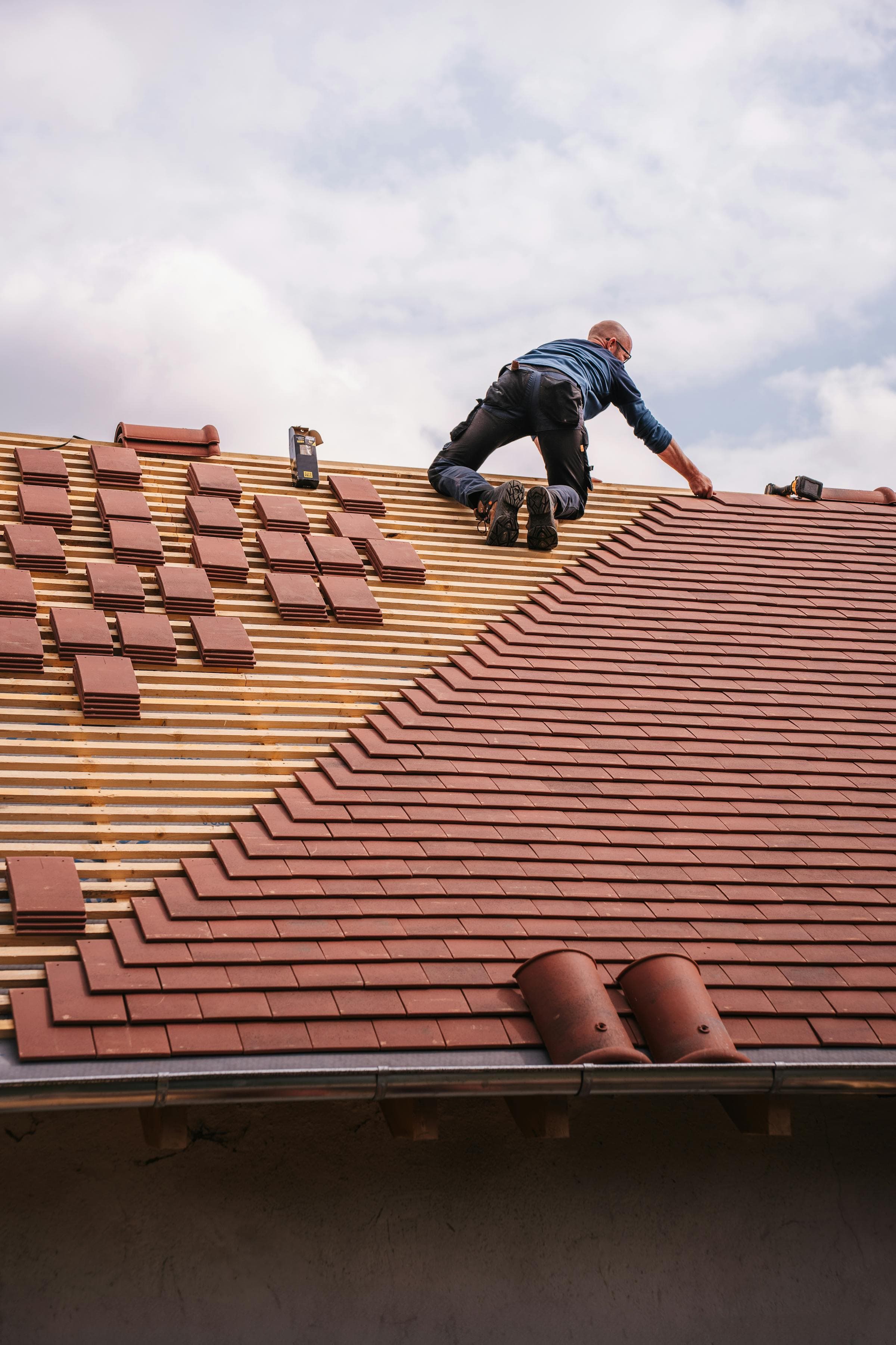 Roofer replacing damaged tiles on a residential roof